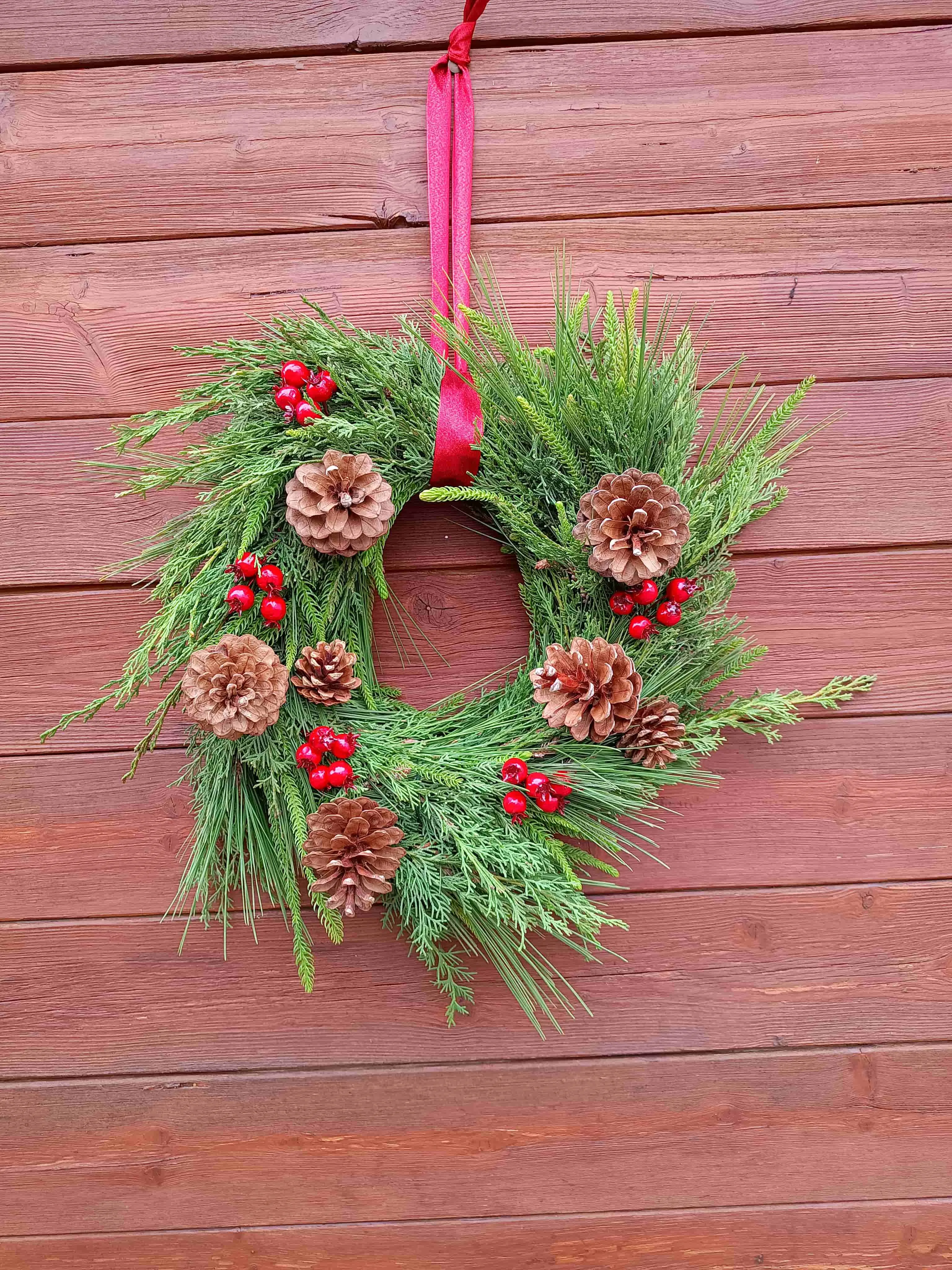 corona con piñas y bolitas rojas
